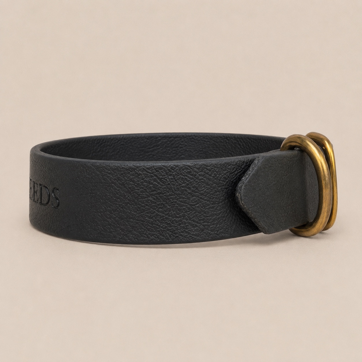 Side detail of the Dirty Leeds® black dog collar showing the strap end and solid brass hardware.