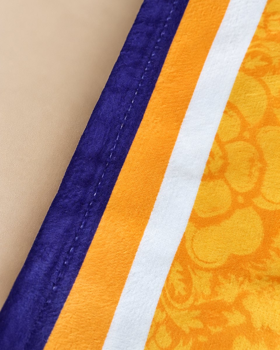 Close-up of the royal blue bound edge and Yorkshire rose pattern on the Dirty Leeds® XL beach towel.