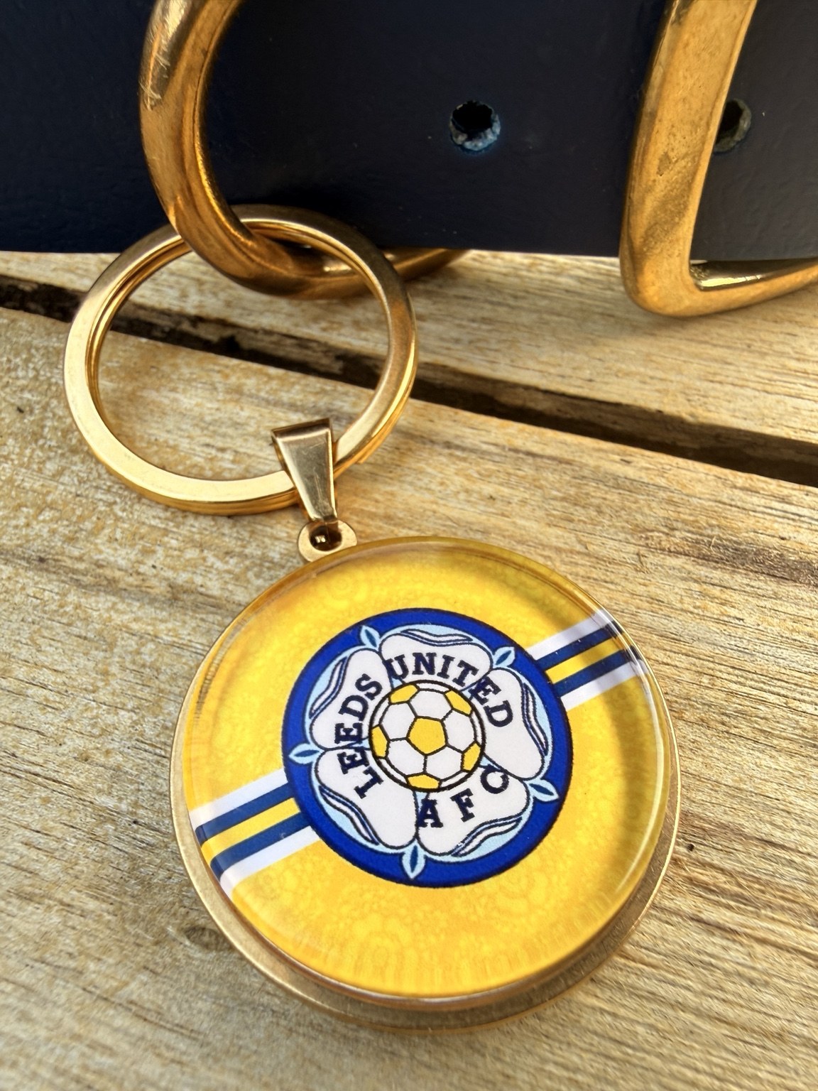 Close-up of the yellow Leeds rose badge keyring with gold-tone hardware.